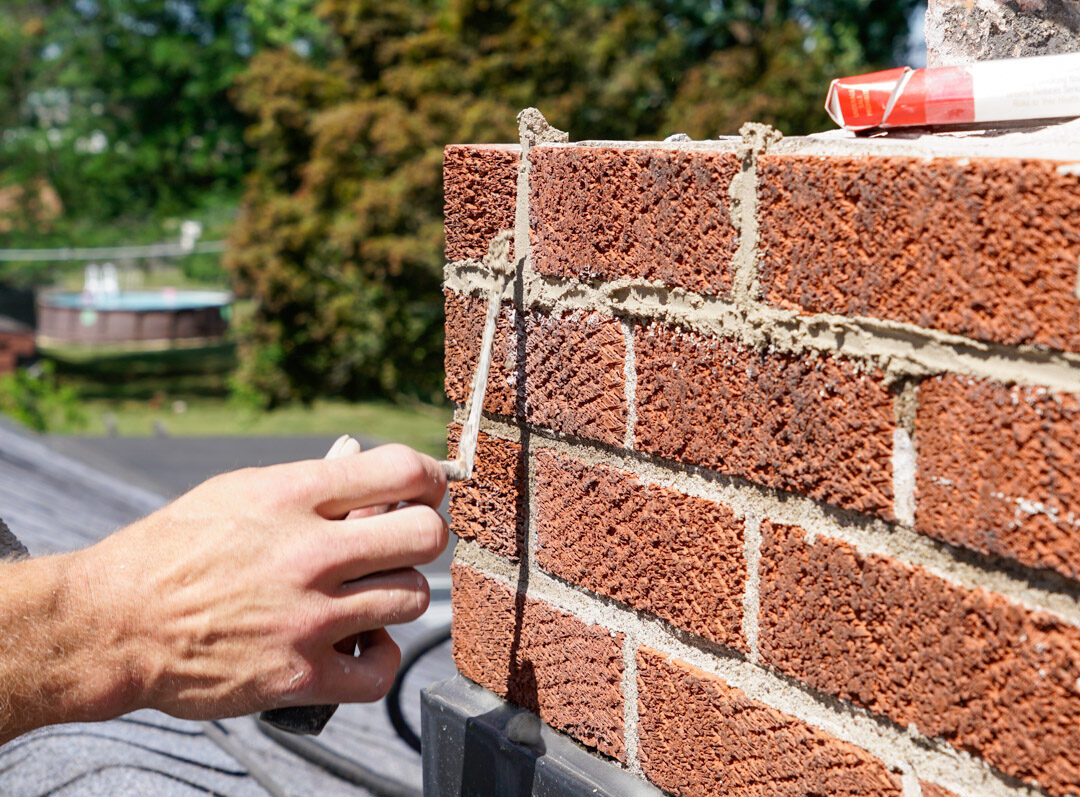 Mason applying fresh mortar to a brick wall joint during tuckpointing