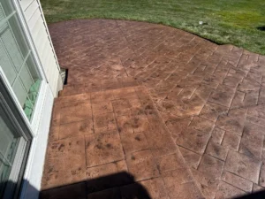Recolored and resealed warm copper toned ashlar slate stamped concrete patio with deep saturated finish at a sided home, by NG Masonry