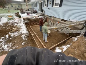 NG Masonry crew framing and laying block for a new home addition foundation in a snowy backyard at a blue sided home, serving Batavia NY