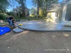 NG Masonry crew saw cutting control joints in a fresh broom finish concrete patio, serving East Rochester NY