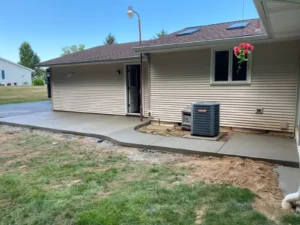 Long broom finish concrete walkway and pad running along a tan ranch home, by NG Masonry serving Greece NY