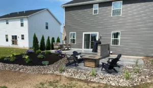 Charcoal slate textured stamped concrete patio in a herringbone pattern between siding and a privacy fence, by NG Masonry serving Williamson NY