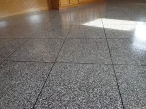 Closeup of a finished gray flake epoxy garage floor coating with shiny topcoat reflecting overhead light, by NG Masonry serving Batavia NY