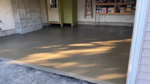 Open two car garage with concrete block foundation walls and a freshly poured smooth gray concrete floor catching afternoon sunlight, by NG Masonry serving Penfield NY