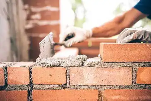 Mason troweling mortar between bricks during a brick repair
