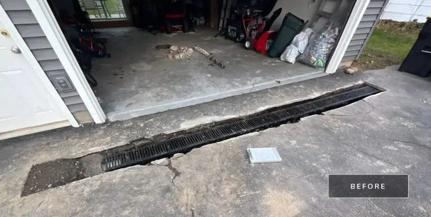 The garage apron in Greece NY before work started, with the drain channel across the opening broken apart and the surrounding concrete cracked and spalling