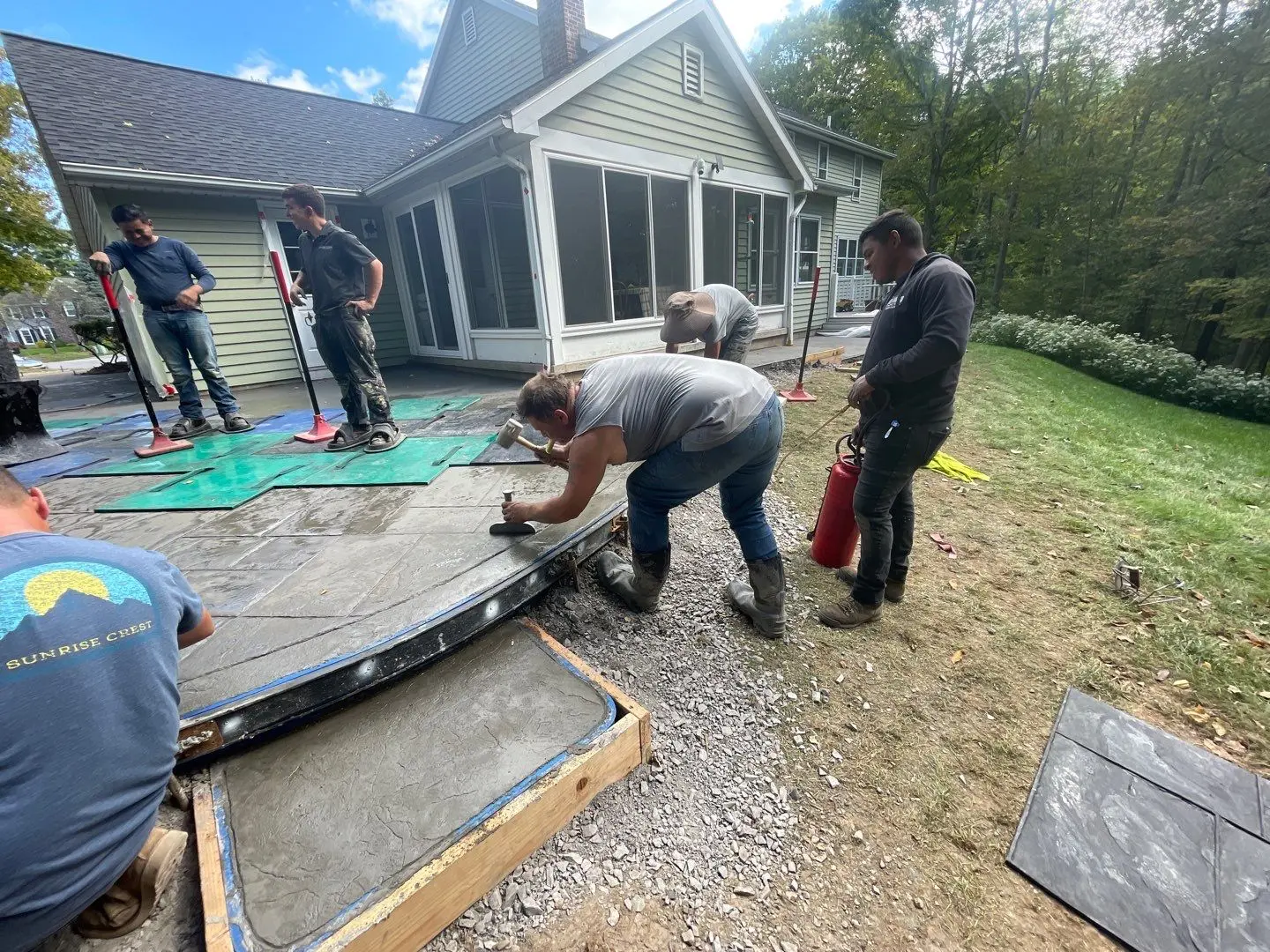 Crew member hand tooling the curved edge of the stamped concrete patio in Pittsford NY