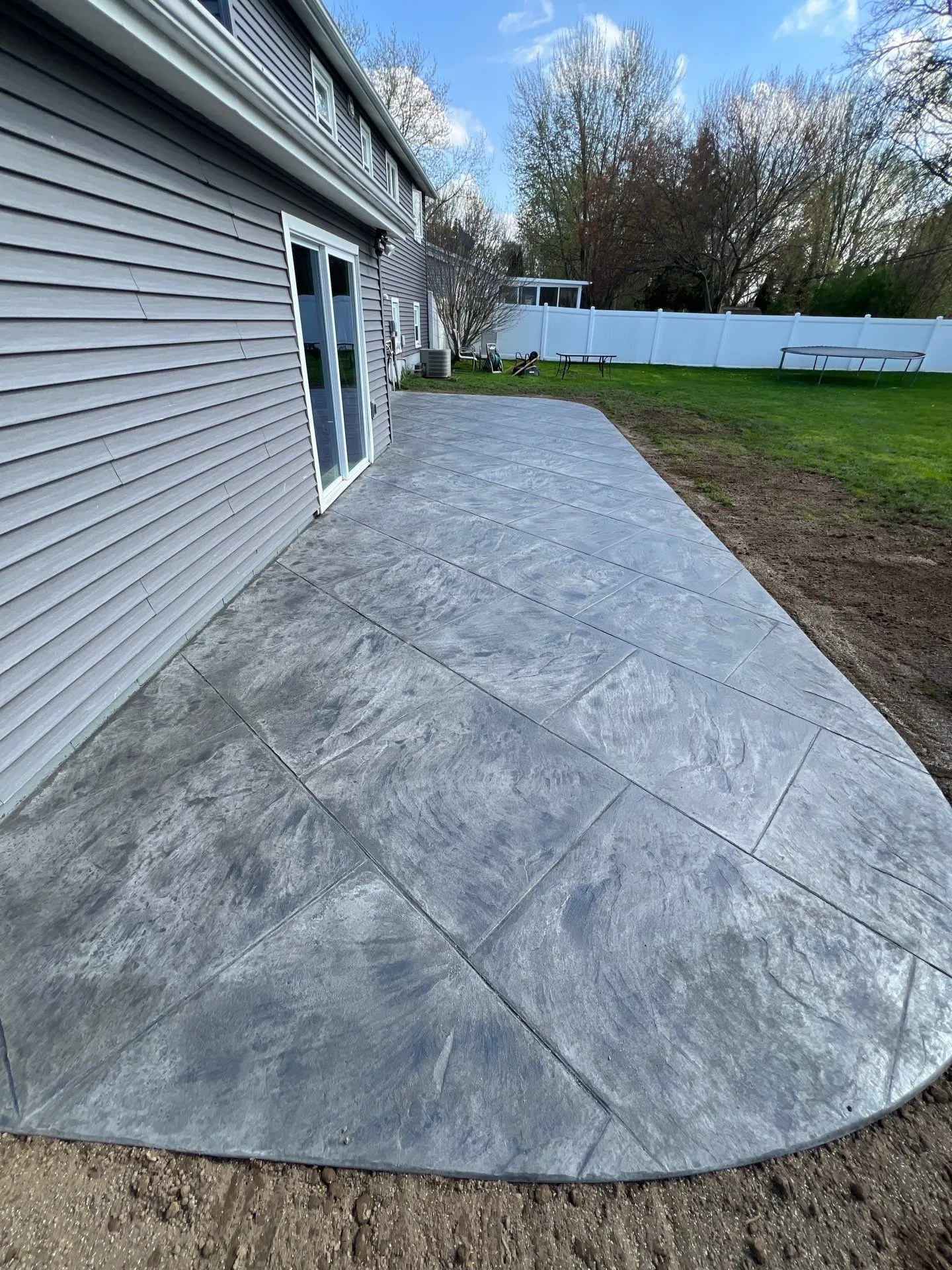 Finished stamped concrete patio in Greece NY running the width of the house with a curved outer corner